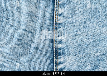 Detailed macro shot of light blue washed denim fabric. Vertical seam with classic orange stitching creates strong line. Perfect for fashion, textile o Stock Photo