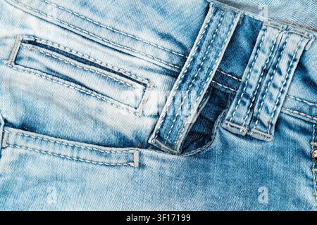 Textured light blue denim fabric with visible seams pocket detail. Soft worn look with natural folds. Neutral lighting highlights weave stitching Stock Photo