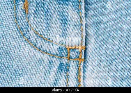 Macro photograph of light blue denim fabric. Detailed texture shows classic jeans fly with yellow stitching and seam. Simple background for fashion, t Stock Photo