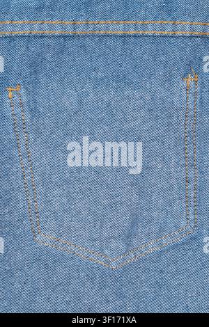 Detailed view of classic blue denim fabric showing back pocket with contrasting orange stitching. Textured weave precise seams highlight craftsmanship Stock Photo