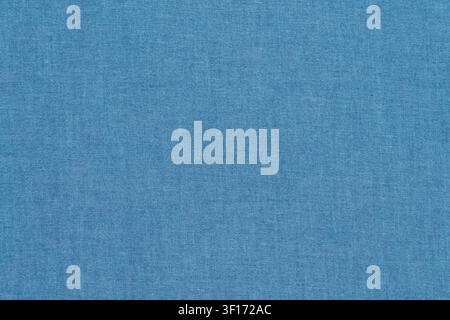 Close up of blue denim fabric with visible weave pattern. Soft even lighting highlights texture. Ideal for design backgrounds, fashion concepts, or te Stock Photo