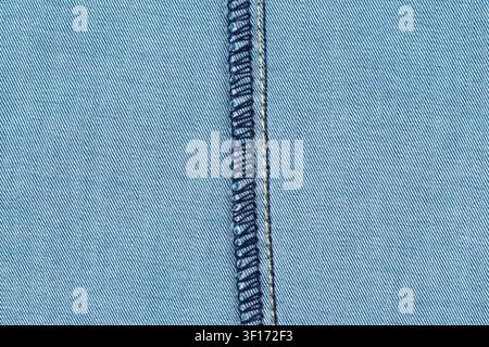 Detailed macro view of light blue denim texture featuring dark blue double stitching yellow thread accent. Soft lighting highlights weave pattern text Stock Photo