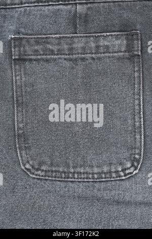 Detailed macro shot of faded black jeans back pocket. Shows classic denim weave seam stitching. Neutral gray tones create versatile background for fas Stock Photo