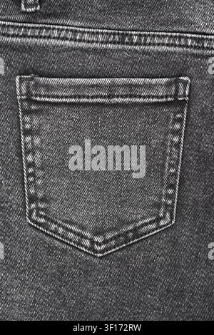 Close up detail shot of back pocket on black denim jeans. Monochrome image highlights fabrics texture, weave and stitching. Great background for fashi Stock Photo