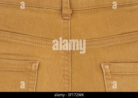 Close up detail of brown mustard color denim pants. Back view showing pockets, yoke, belt loop and stitching. Flat lay composition highlights fabric t Stock Photo
