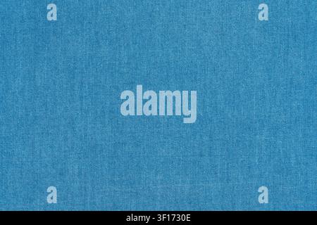 Close up of blue denim fabric with visible weave pattern subtle texture. Even lighting highlights natural fiber details. Ideal for backgrounds, design Stock Photo