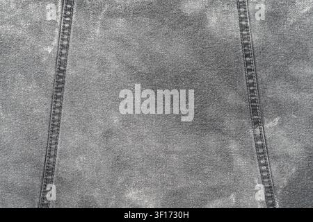 Textured gray denim surface with parallel double stitching lines. Worn fabric with subtle fading natural weave pattern. Neutral tones, soft lighting, Stock Photo