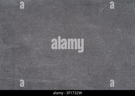 Closeup of dark gray denim fabric with visible weave pattern subtle texture. Neutral tone uniform surface ideal for design overlays, product mockups, Stock Photo