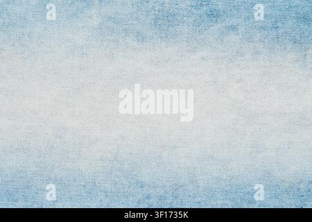Closeup top view of light blue denim fabric. Stonewashed jeans material shows detailed diagonal weave and faded white center. Neutral, versatile texti Stock Photo
