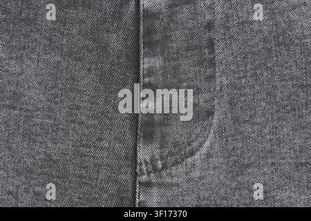 Close up view of black denim textile. Detailed macro shot shows twill weave, vertical seam, and fly stitch. Neutral gray fabric background for fashion Stock Photo