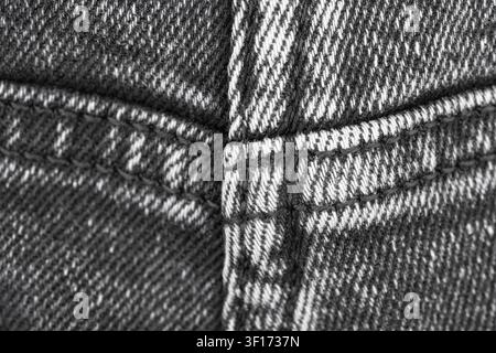 Close up view of black denim fabric texture with visible stitching. Detailed macro shot of cotton jeans garment material. Textile background for fashi Stock Photo