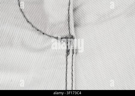 White denim fabric detail with fly seam. Closeup of cotton jeans texture and heavy stitch construction. Fashion garment material background for clothi Stock Photo