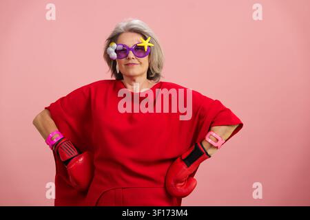 Senior woman posing with boxing gloves and whimsical sunglasses Stock Photo