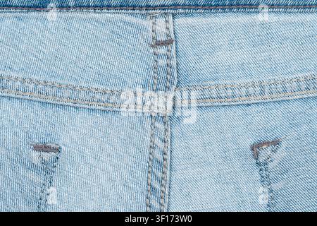 Closeup of light blue denim fabric showing detailed stitching, texture, worn areas. Soft natural lighting highlights weave pattern subtle fading Stock Photo