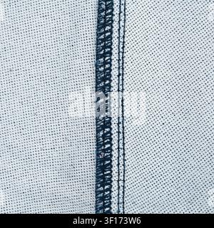 Detailed view of light blue denim with dark blue seams visible thread texture. Natural lighting highlights fabric grain stitching precision Stock Photo