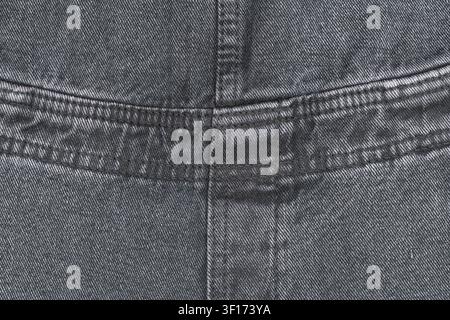 Detailed macro shot of dark gray denim fabric. Shows texture, weave, and stitching on seam. Rugged, durable textile background for fashion or design c Stock Photo