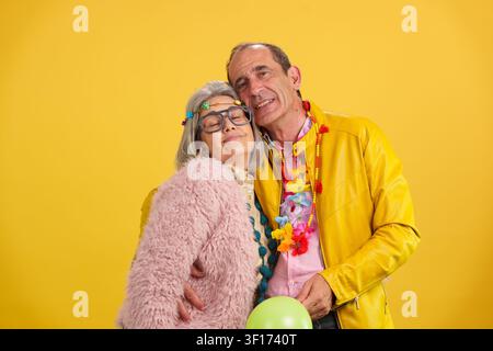 Senior couple smiling and embracing, dressed in colorful party clothes Stock Photo
