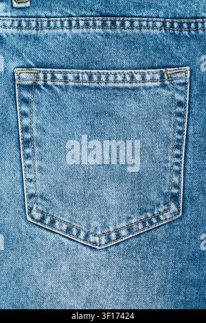 Close up detail of classic blue denim jeans back pocket. Textured fabric background with yellow seam stitching. Simple, clean composition for fashion Stock Photo