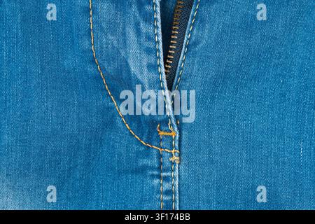 Detailed macro shot of blue denim jeans fabric. Focus on brass zipper, fly and contrasting yellow stitching. Perfect background for fashion, textile, Stock Photo