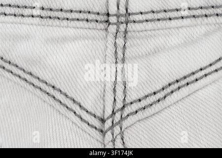 Flat lay top view of light denim fabric with gray stitching forming geometric patterns. Minimalist composition highlights textile weave seam details Stock Photo