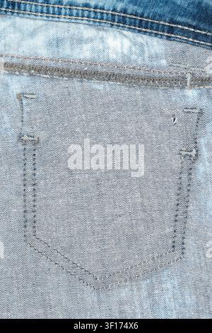 Detailed view of back pocket on light blue denim jeans showing texture, stitching, wear patterns. Soft natural lighting highlights fabric weave faded Stock Photo