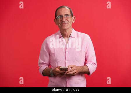 Mature man smiling using smartphone for positive longevity Stock Photo