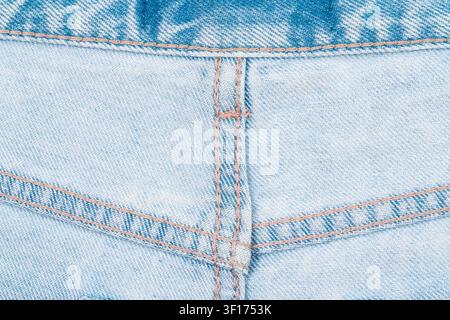 Macro shot of light blue denim fabric showing detailed weave beige stitching. Soft natural lighting highlights texture wear patterns. Ideal for fashio Stock Photo