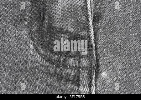 Close up view of black denim fabric with stitched seam and fly edge. Textured cotton material for jeans background. Fashion apparel surface detail for Stock Photo