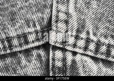 Macro detail of grey denim fabric with visible stitching. Textured acid wash cotton textile pattern. Clothing material background for fashion design, Stock Photo
