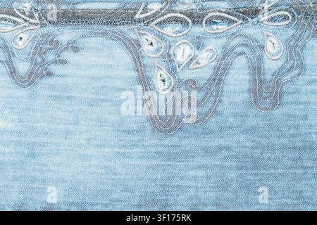 Close up of light blue denim with intricate white embroidery gray stitched designs. Soft texture detailed craftsmanship. Ideal for fashion, textile, d Stock Photo