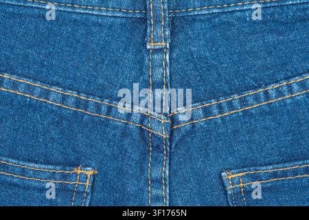 Detailed macro shot of blue denim fabric. Close up view shows classic yellow stitching on back pocket and yoke seams. Perfect texture or background fo Stock Photo