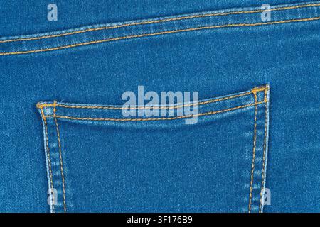 Detailed closeup of classic blue denim fabric. Features back pocket with double orange stitching and seam. Macro shot shows canvas texture. Ideal for Stock Photo