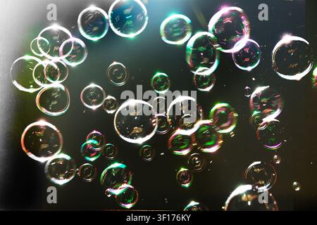 Bubbles floating against a black background, with rainbow colours Stock Photo