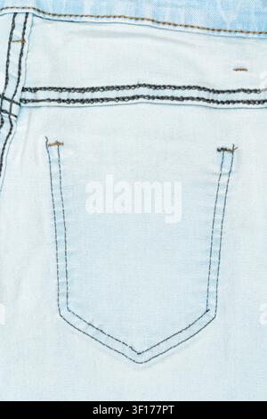 Light blue denim fabric close up showing back pocket with dark contrast stitching. Textured weave seam details under even lighting Stock Photo