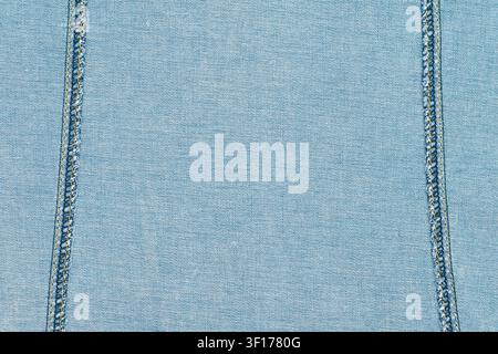 Closeup of light blue denim textile with parallel double stitching in yellow and blue thread. Even lighting highlights texture and weave. Ideal for fa Stock Photo