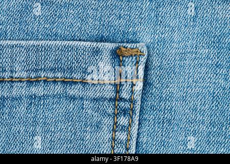Extreme close up of blue denim back pocket. Detailed jeans fabric texture with contrast orange stitching showing material quality and craftsmanship. F Stock Photo
