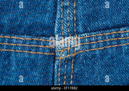 Denim texture with brown stitching detail, three needle job. Closeup of blue jeans fabric construction. Durable cotton material for clothing manufactu Stock Photo
