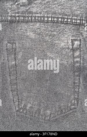 Detailed view of worn gray denim fabric showing pocket seam and weave texture. Soft lighting highlights natural fading and thread patterns. Ideal for Stock Photo
