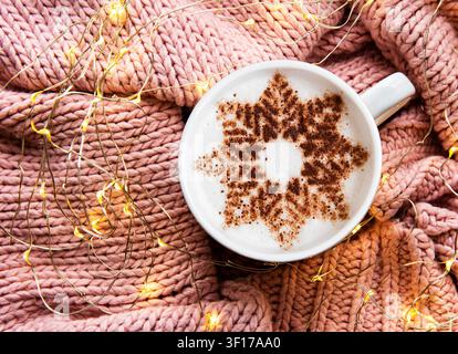 Coffee with a snowflake pattern on a warm knitted sweater background. Top view Stock Photo