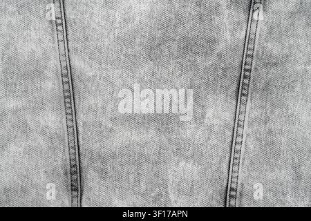 Close up of light grey acid wash denim fabric. Diagonal twill pattern, texture, and two vertical seams with dark stitching are visible. Neutral, casua Stock Photo