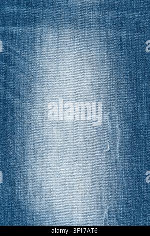 Closeup of worn blue denim texture. Faded jean fabric background with visible diagonal weave and creasing. Perfect for design, wallpaper or fashion co Stock Photo