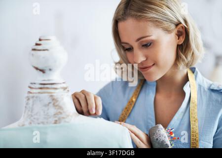 Pin, design and woman with mannequin in startup, adjusting and fashion designer with measuring tape. Checking, seam and happy person with sewing Stock Photo