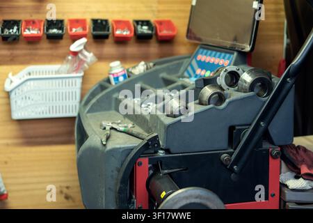 A workbench holds various tools and equipment for repair tasks. Supplies are neatly arranged on shelves. A computer screen displays useful information Stock Photo