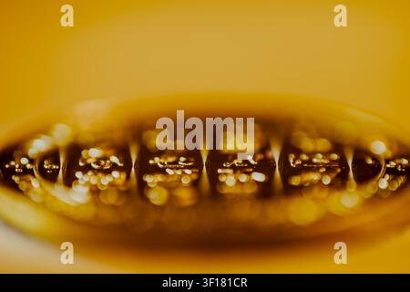 A conceptual macro photograph featuring a golden metallic surface with sparkling, out-of-focus bokeh lights against a warm, minimalist yellow backgrou Stock Photo