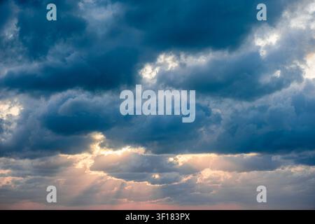 Dramatic sky with clouds and sunlight breaking through at sunset. Stock Photo