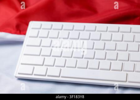 An angled shot of a white computer keyboard without letters resting on an Indonesian or Polish flag backdrop. High Quality Photo Stock Photo