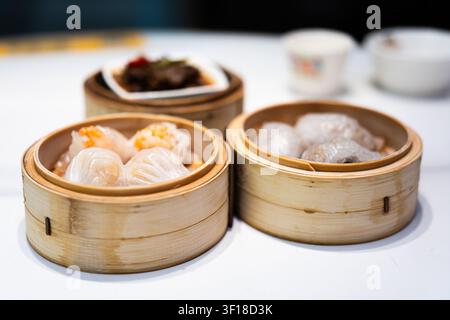 Hong Kong, China – Authentic Dim Sum in Bamboo Steamers: Shrimp Dumplings and Har Gow on White Table Stock Photo