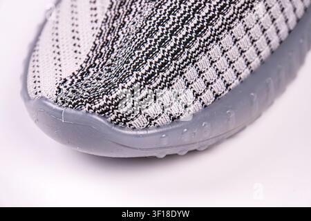 Close-up of modern shoe, showcasing knitted upper material, intricate pattern, translucent rubber sole, high-quality construction, studio lighting, cl Stock Photo