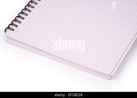 Close-up notebook with spiral binding, grid lines on pages, diagonal composition, clean white background, professional studio lighting, emphasizing te Stock Photo
