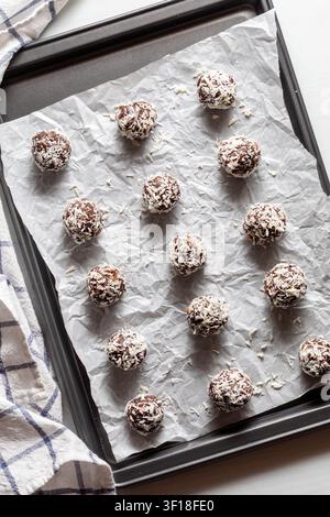 Coconut covered cocoa energy balls on a parchment lined baking sheet. Stock Photo